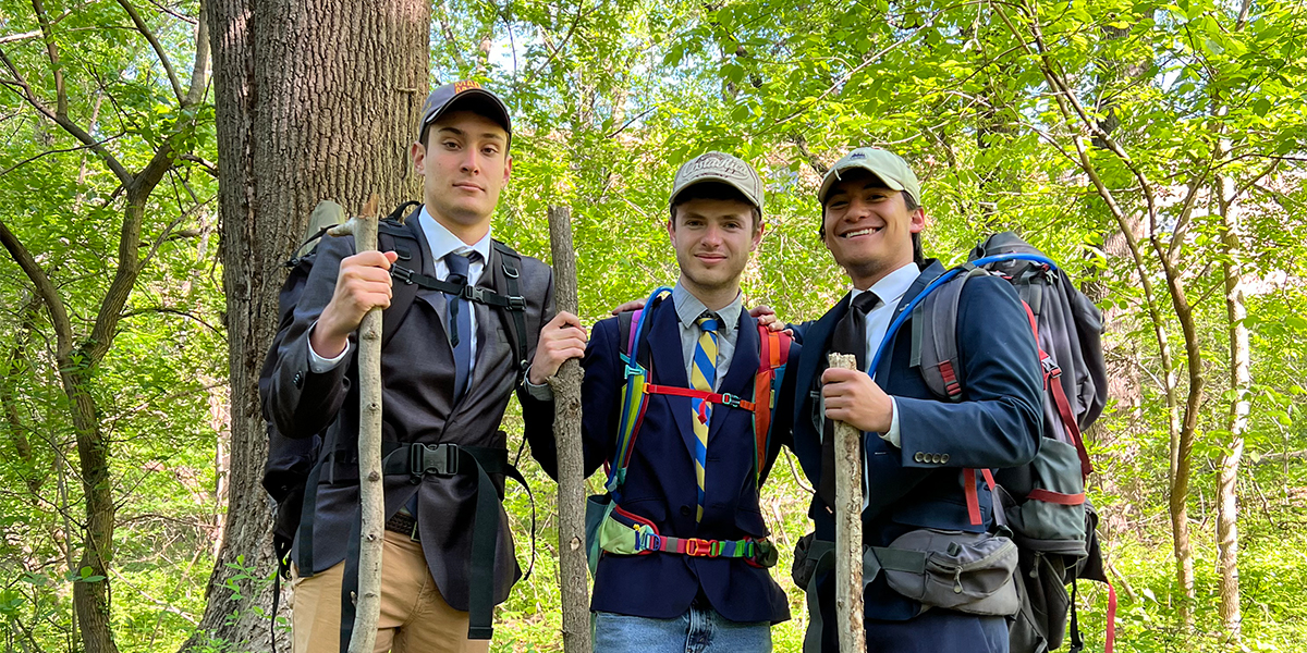 Daniel Levy, Jacob Rosenbloom and Jacob Rosenblatt outside with walking sticks and looking ready to hike.