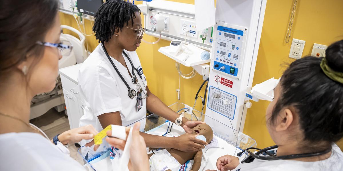 Nursing student working with baby manikin.